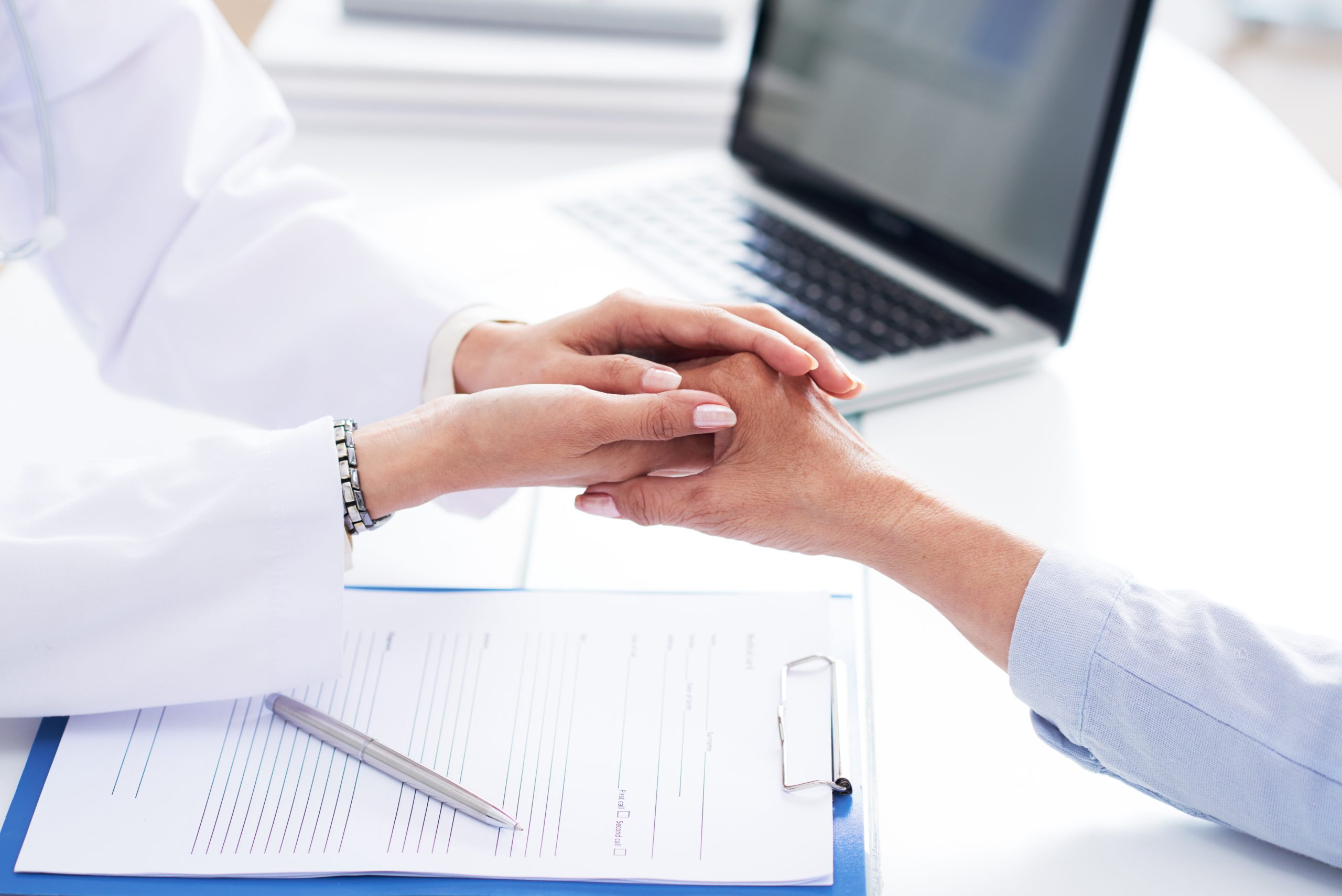 Close-up image of doctor holding hand of senior patient to support